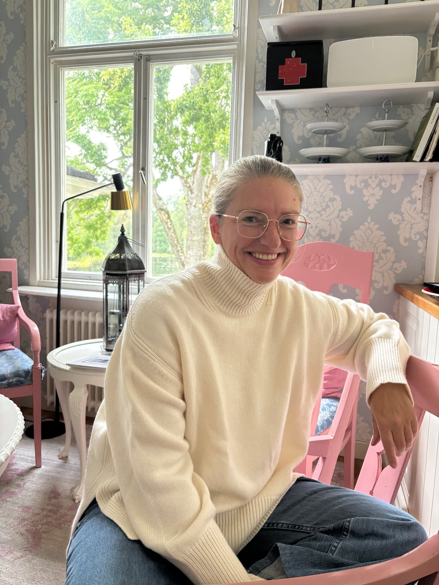 Annika Telléus sitter i en rosa stol vid ett fönster
